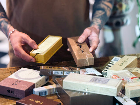 A man with tattoos arranging boxes of incense