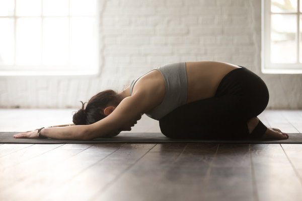 woman in child's pose on yoga mat