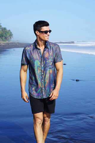 a man in a holographic T-shirt walking on the beach