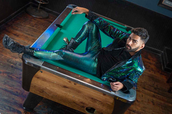 A man in a sparkly jacket lying on a pool table