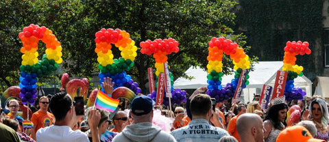 Letters made of rainbow balloons spell out “Pride” in a crowd of parade-goers