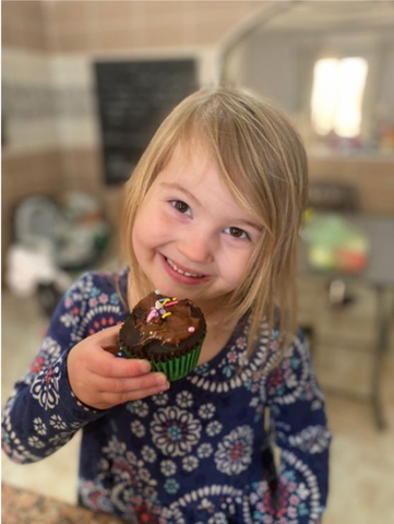 Daughter smiling at her purdate chocolate cupcake.