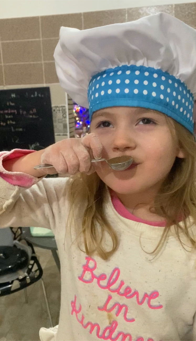 Kid baking, holding ingredients up to her nose.