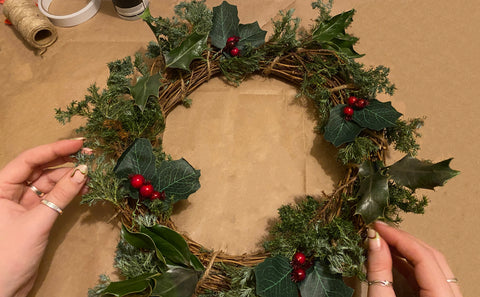 Weaving the holly sprigs and plant clippings into the ring