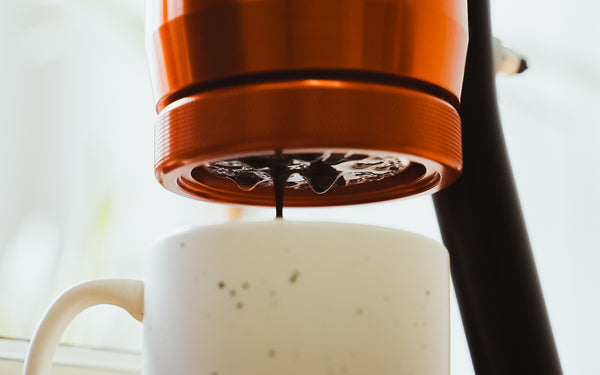 Coffee dripping from espresso basket as espresso extraction begins.