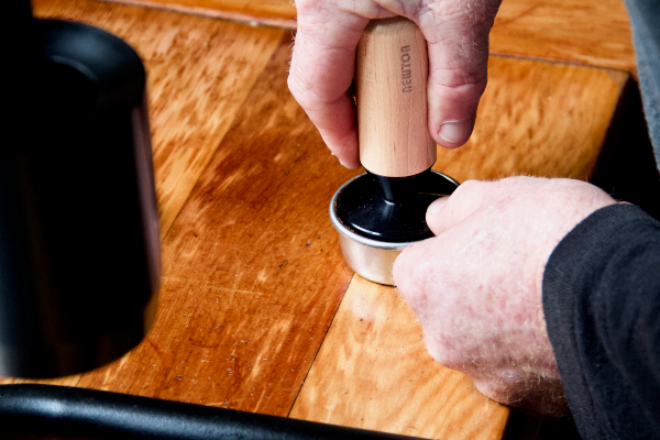 Tamping a coffee basket using coffee tamper with wooden handle