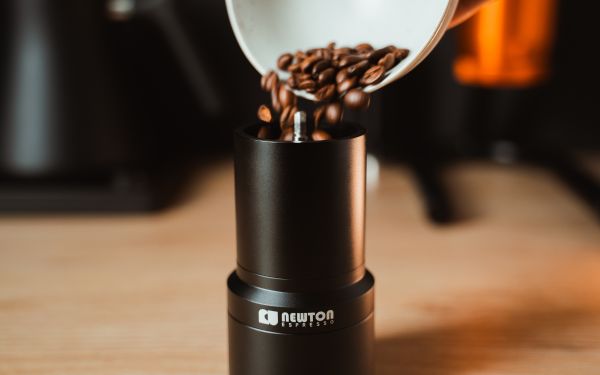 Coffee beans pouring into the Newton Espresso hybrid coffee grinder.