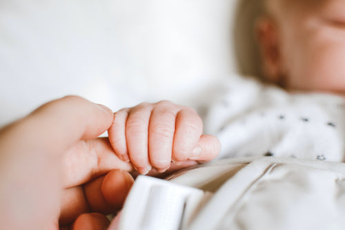 baby holding mother's finger