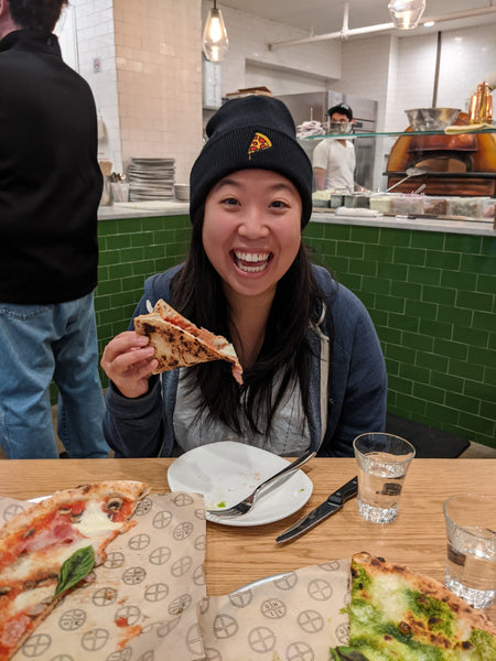 Jenn eating pizza while wearing a pizza hat