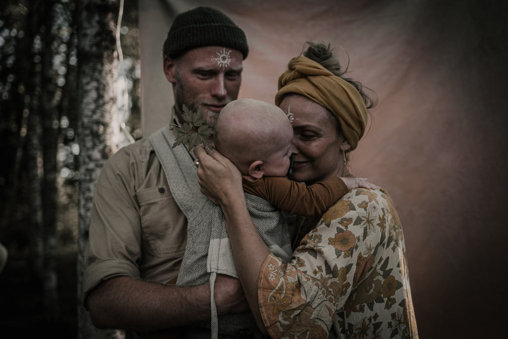 Mann und Frau mit Baby in der Trage