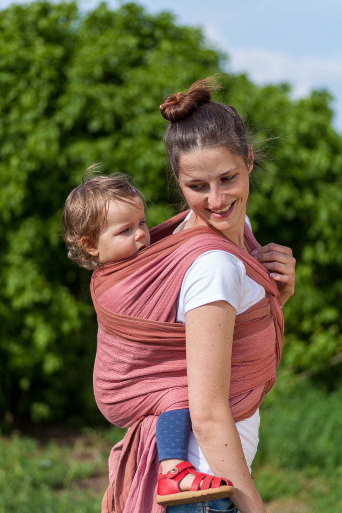 Frau mit Baby auf dem Rücken gebunden im Mama Nuka Tragetuch