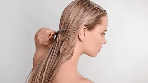 Bilden visar en kvinna i profil som kammar igenom sitt våta, balsambehandlade hår. Hon har en koncentrerad blick och ser ut att vara noggrann med sin hårvård. Man kan se balsamets textur i håret som blir utkammat.