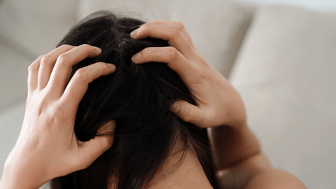 Bilden visar en person som klöser sig i huvudet, vilket kan vara ett tecken på hårbottenproblem som mjäll eller klåda.