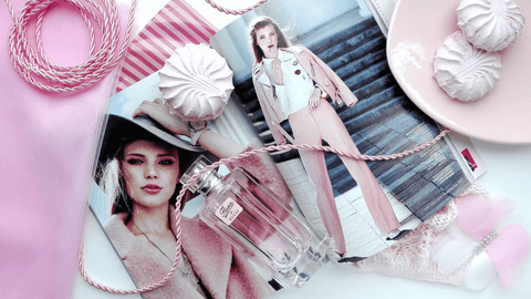 En estetiskt anordnad komposition med en 'Flora by Gucci' parfymflaska, en modetidning, rosa sidenband och maränger, allt i en harmonisk pastellrosa färgsättning.