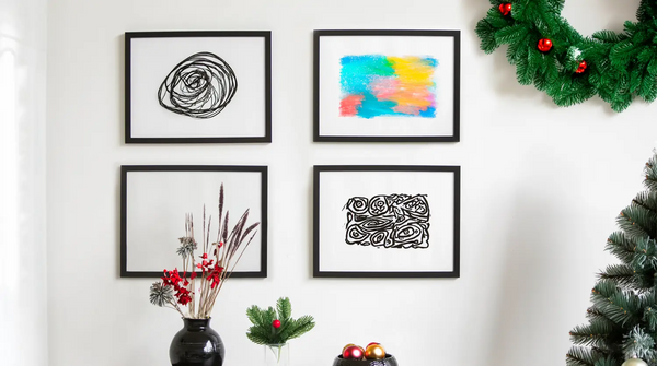 Four frames on the wall with holiday decorations surrounding it
