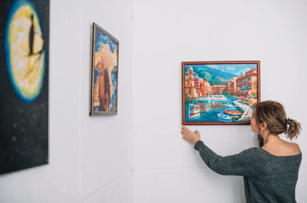 A woman hanging up a painting