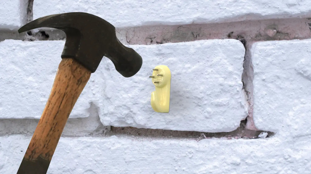 A hammer and a plastic hardwall hook on a brick wall