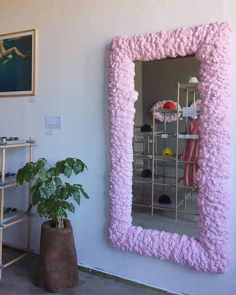 A pink foam mirror hanging on a wall
