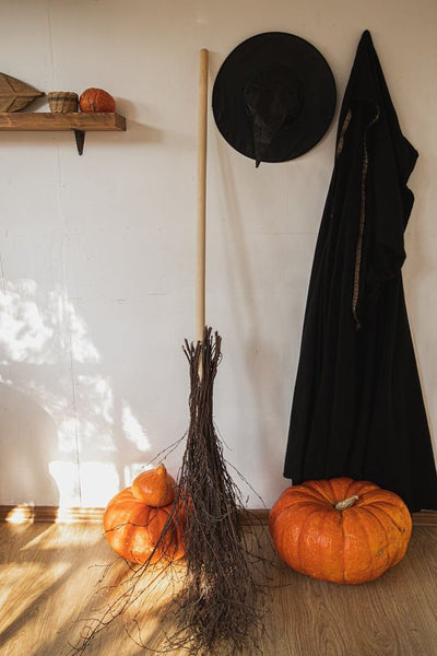 A witch's broomstick, robe, and pumpkins in Halloween decor