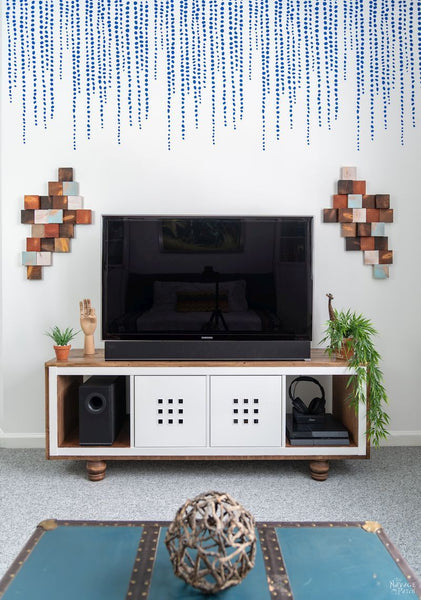 Painted wooden blocks hung as a decorative wall hanging on a TV wall