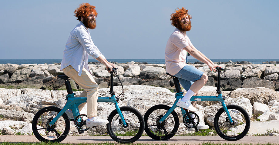 Two men riding electric bikes on the beach