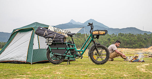 Man camping with an electric bike next to him