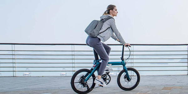 A woman riding a folding e-bike with bag on her back