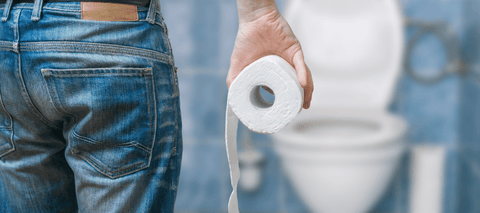 Man standing in front of toilet holding toilet paper