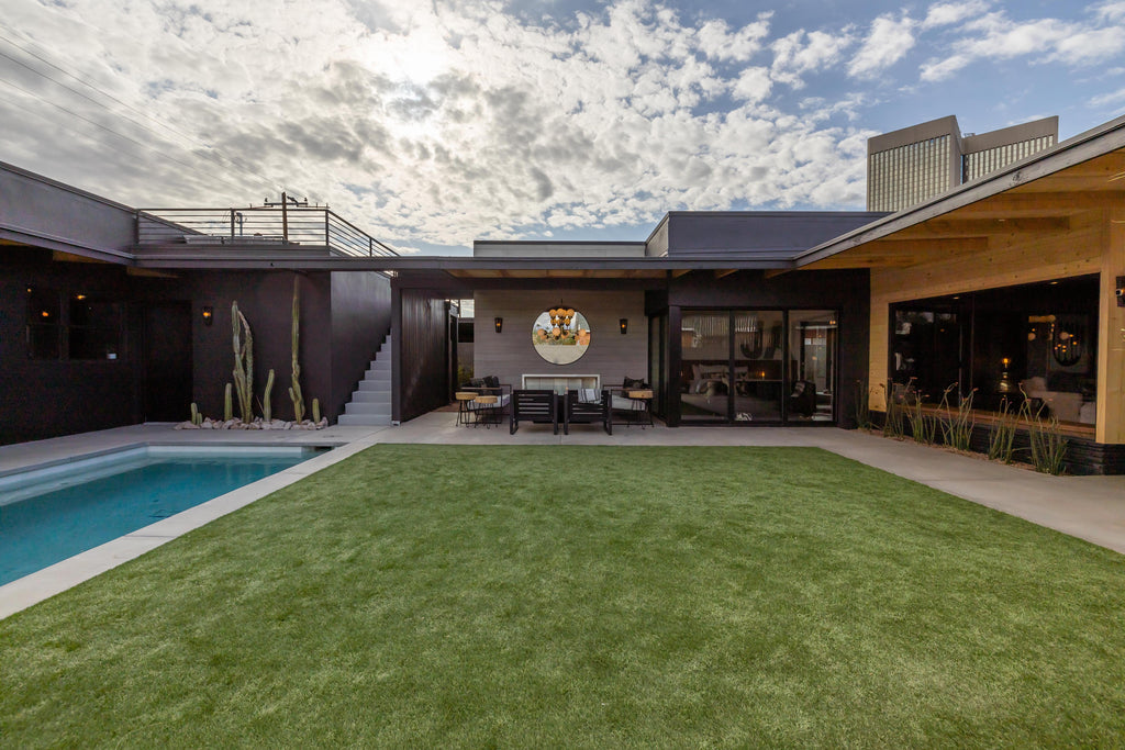 James Judge woodward outdoor transformation showing a grassy area, pool, and outdoor fireplace with black furniture and a grey board-formed concrete feature wall