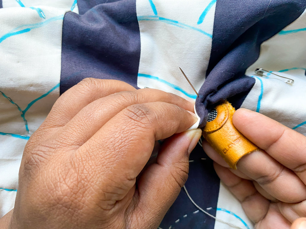 using a thimble and middle finger to push needle through quilt