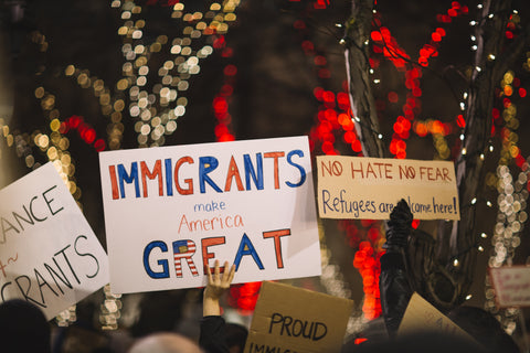 Person holding a Immigrants are Great sign at an event.