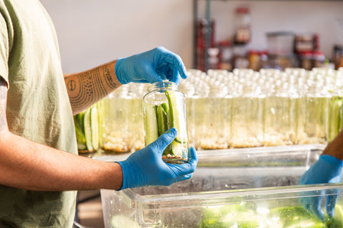 Hand packing a jar of pickles