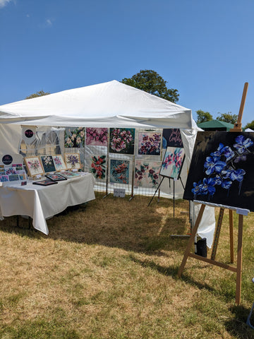 Art fair gazebo set up by Judy Century with floral paintings