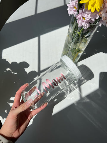 A glass, reusable bubble tea cup that has "#1 MOM" in metallic pink cursive font printed on it