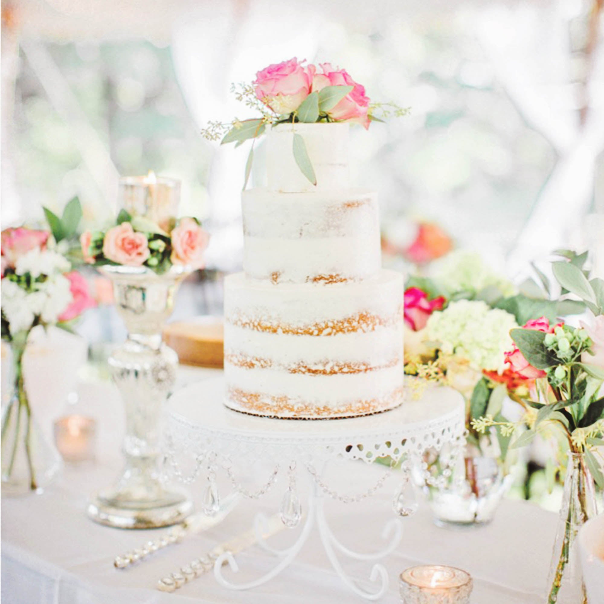 semi naked wedding cake on white chandelier cake stand