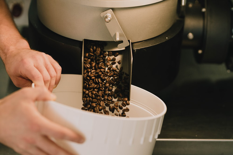 Coffee beans being poured from a roasting drum into a container