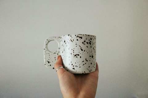 A person holding a black and white coffee mug.