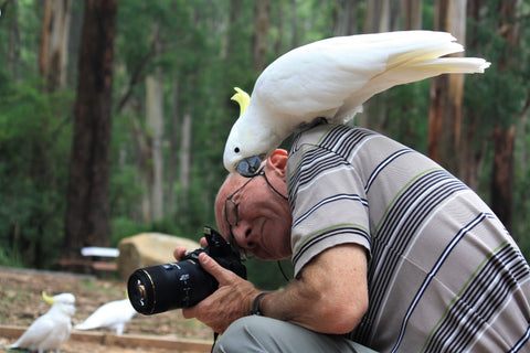 photographer in the wild with bird on his shoulder