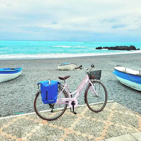 wasserdichte blaue Fahrradtasche am Strand hintergrund das Meer türkis 