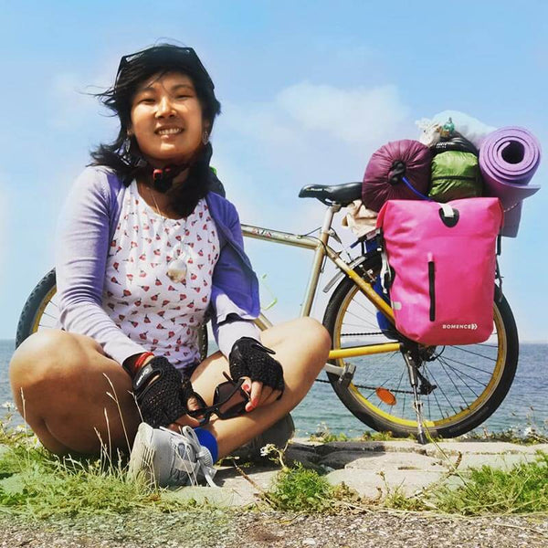 Vrouw die alleen reist op fietstocht met fietstassen op het strand, gevoel van vrijheid