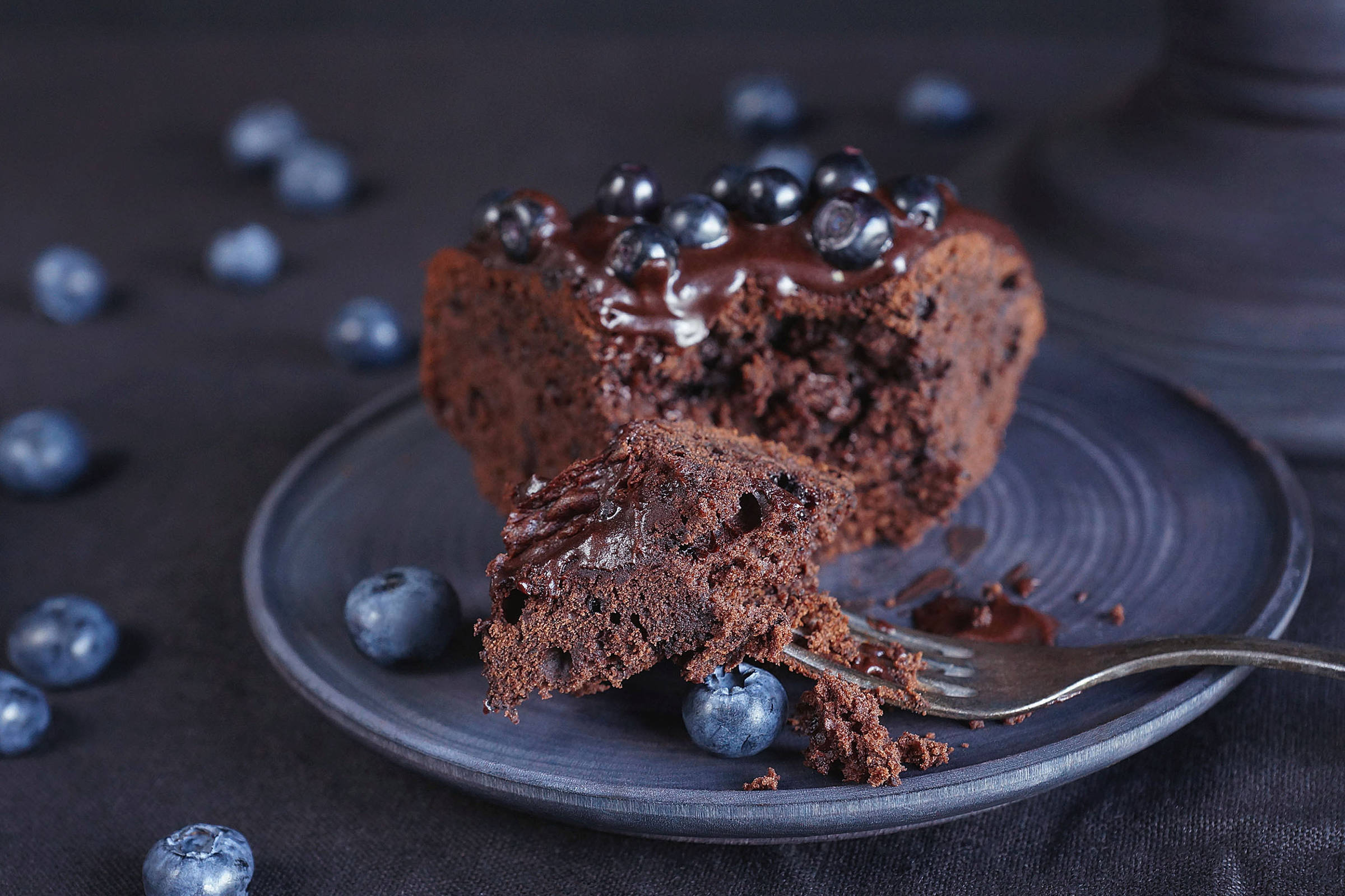 Slice of blueberry chocolate cake on a plate with a fork.