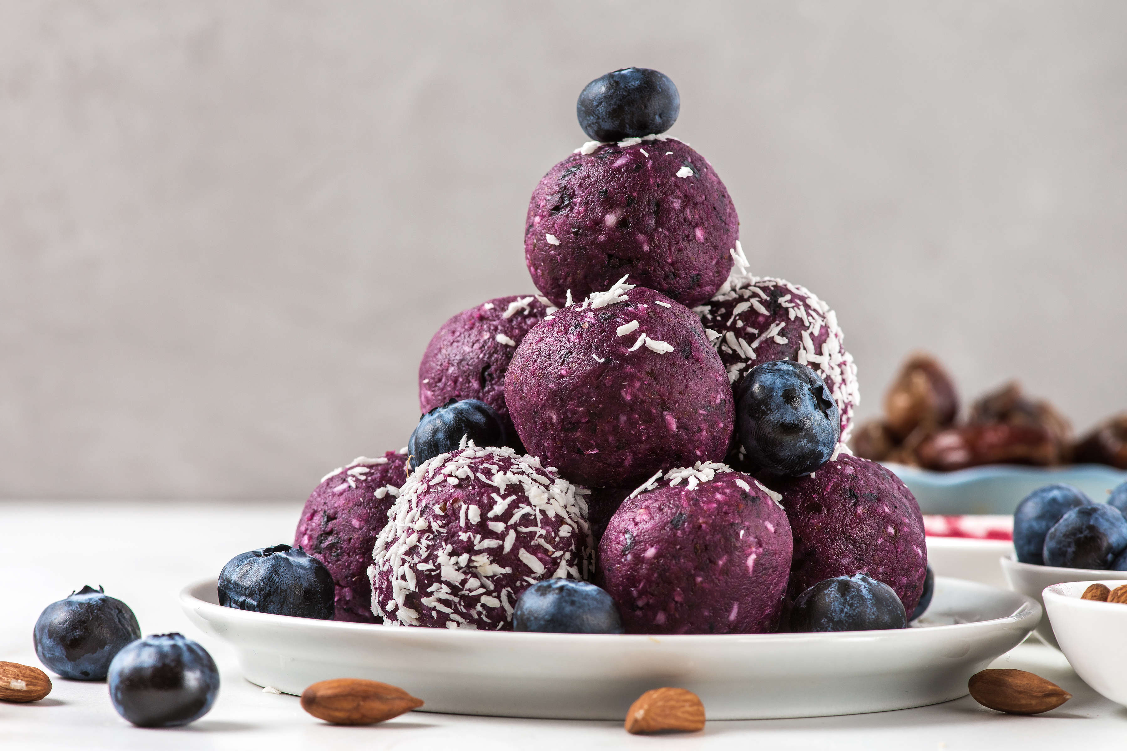 Blueberry energy balls stacked on a plate.