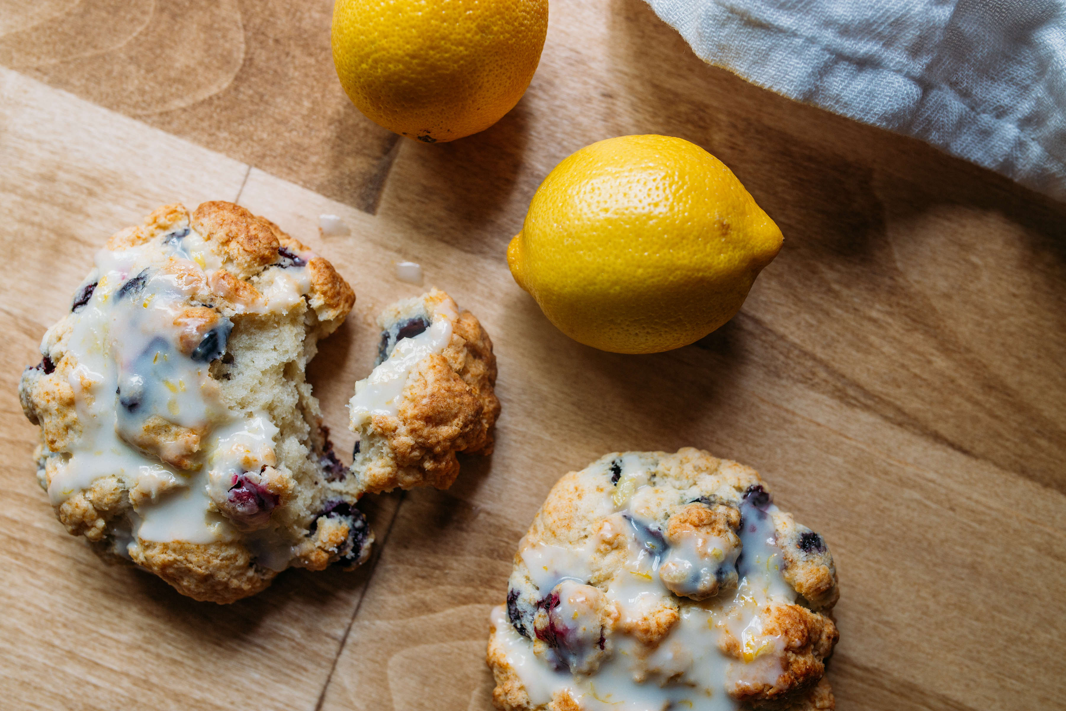 Blueberry muffin biscuits on a wooden serving board, next to some fresh lemons.
