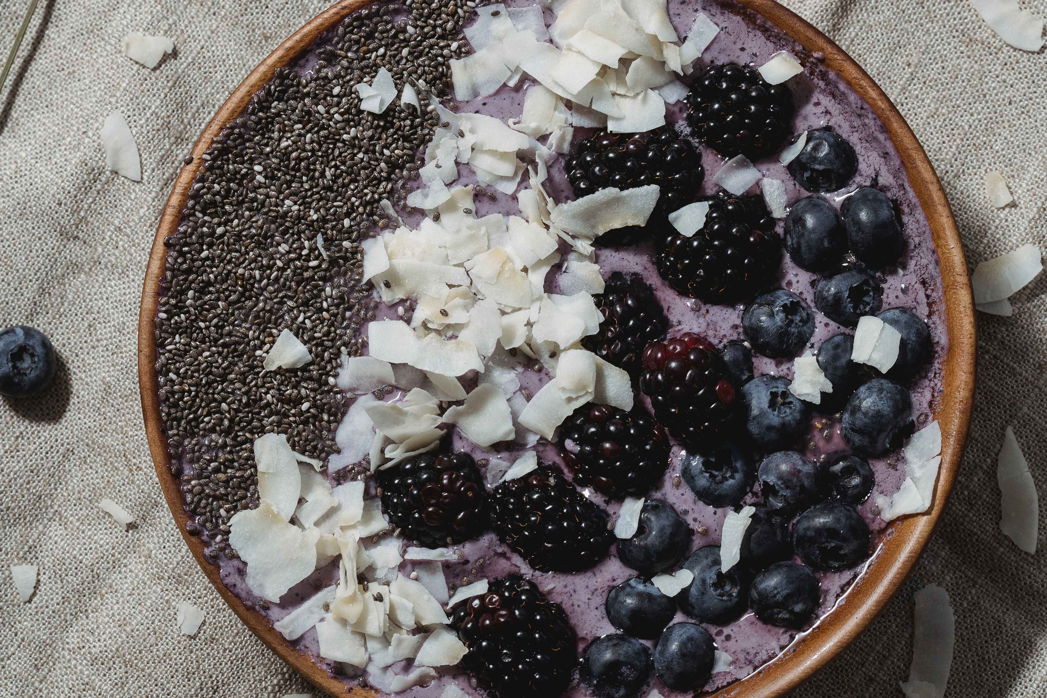 Blueberry smoothie bowl topped with chia seeds, flaked coconut, and mixed berries.