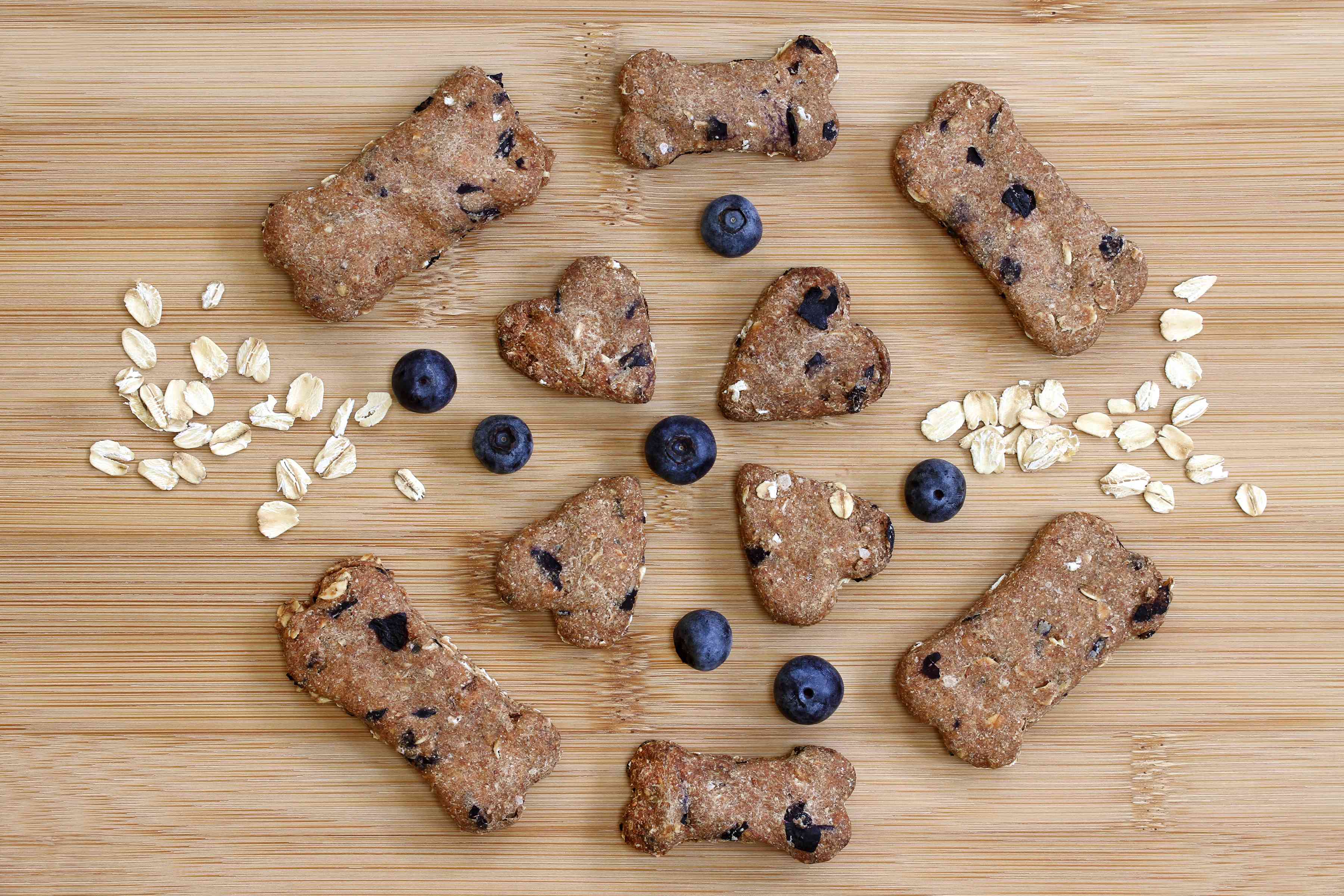 Heart and bone shaped blueberry dog treats arranged on a wooden board.