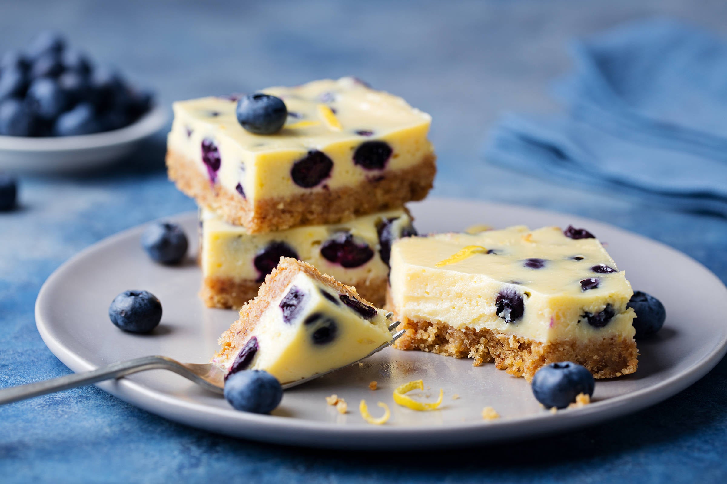 Blueberry bars, cake, cheesecake on a grey plate on blue stone background