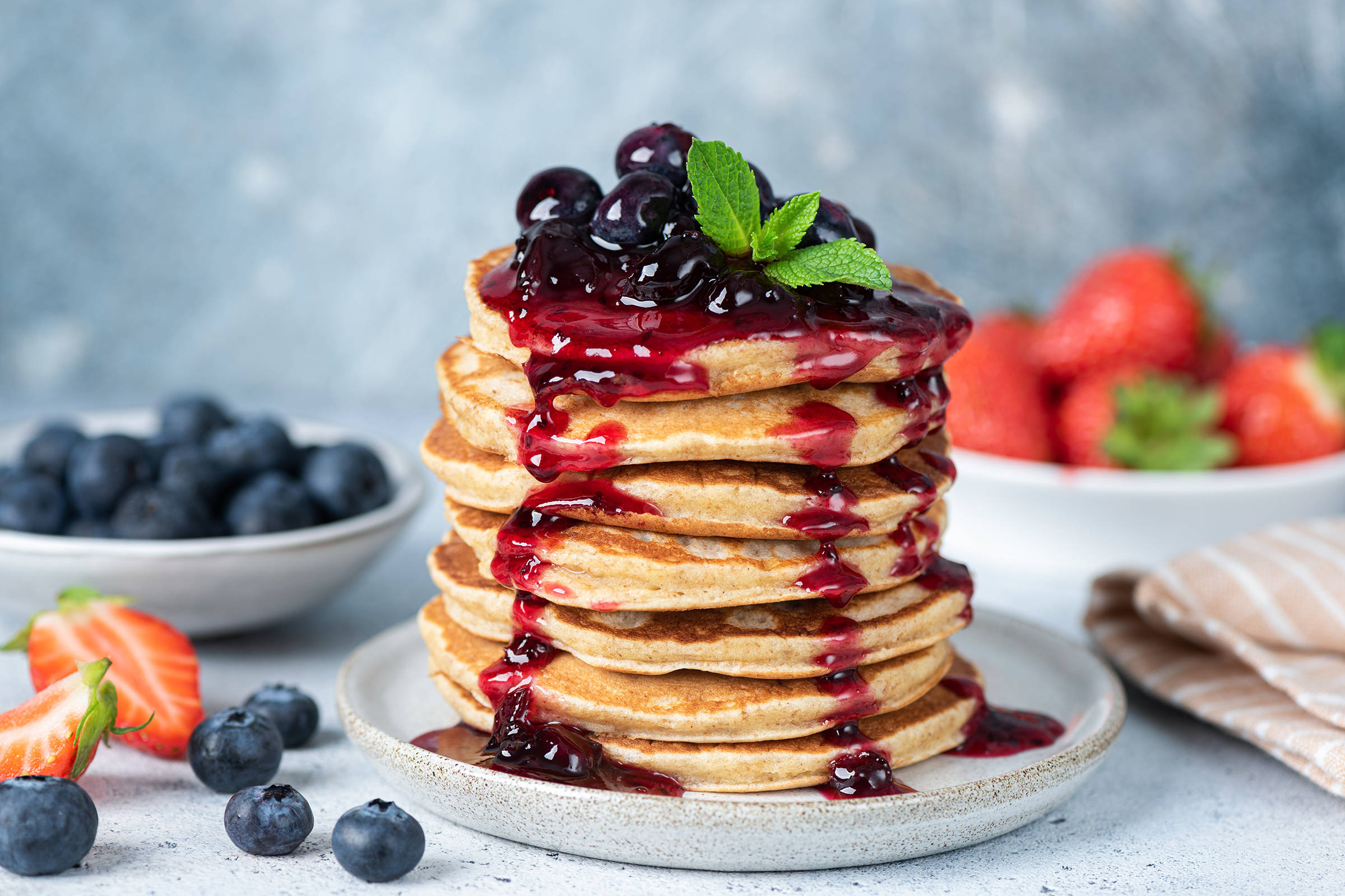 Delicious oatmeal pancakes with berry fruit blueberry strawberry jam dessert topping. Blue background