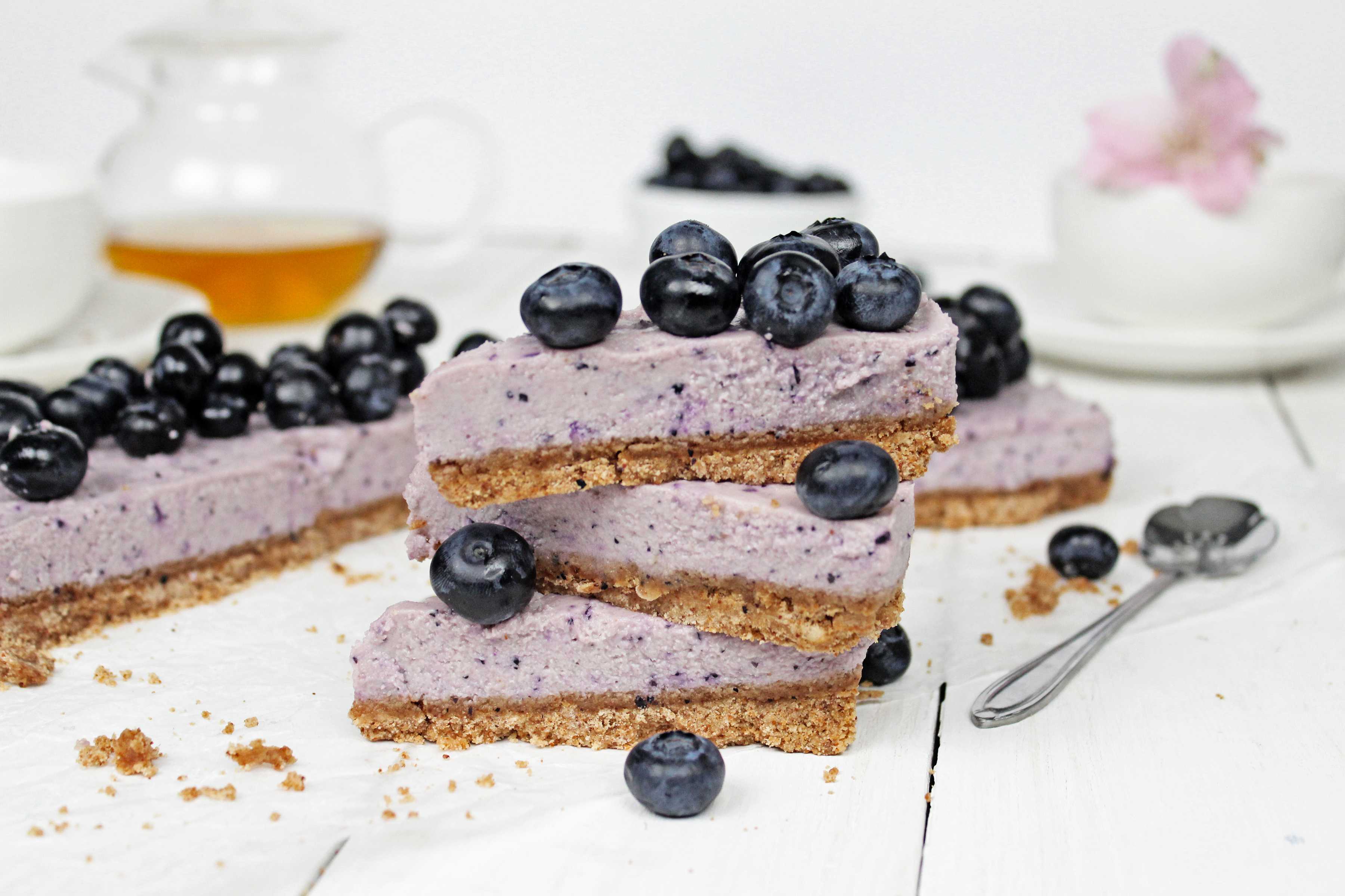 Slices of raw vegan blueberry cheesecake topped with fresh blueberries.