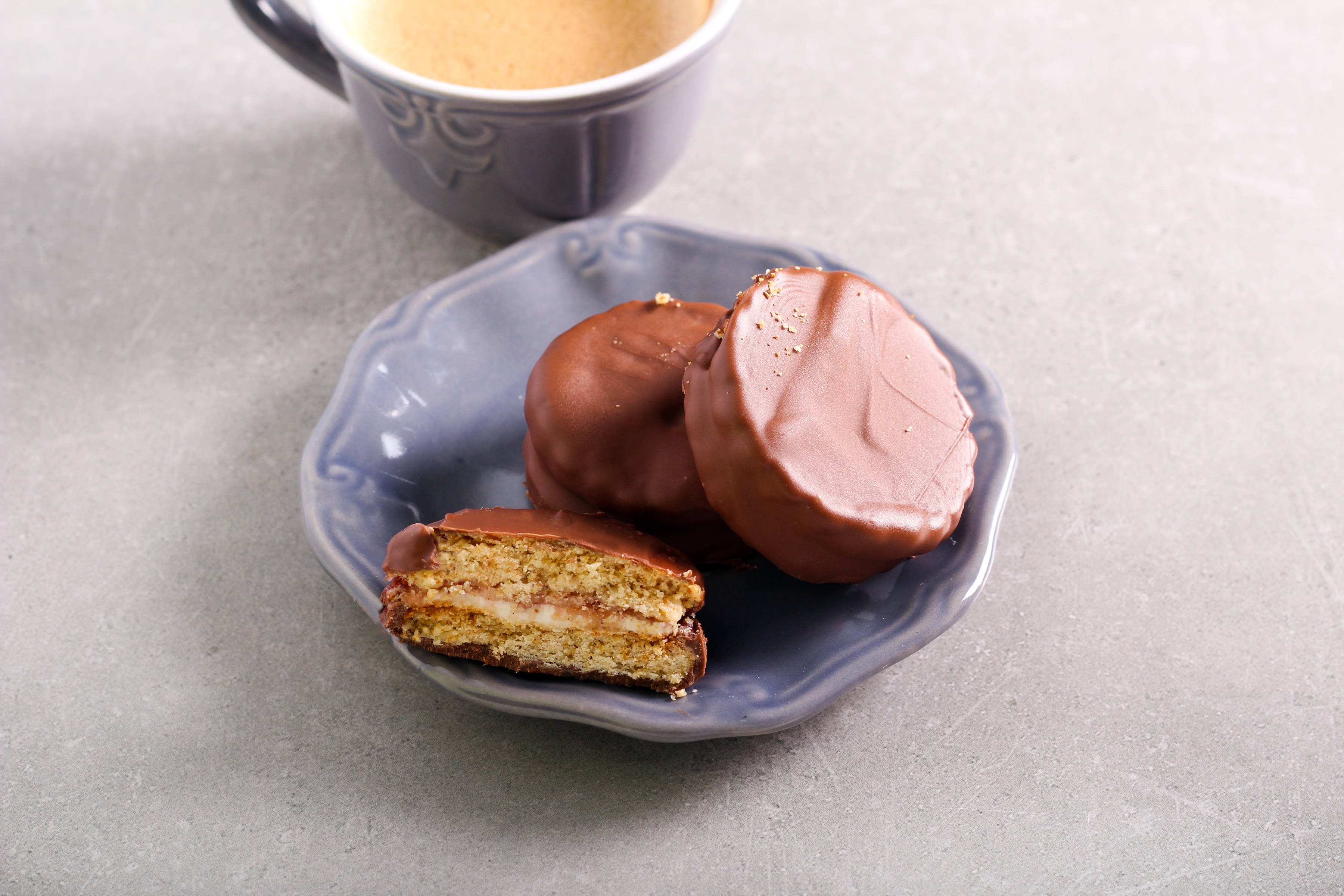 Wagon wheel biscuits on small plate next to a hot beverage.