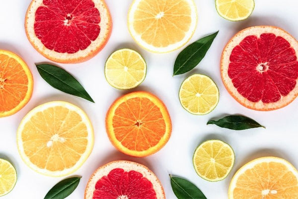 bright slices of citrus fruits: grapefruit, lemon and orange. laid out on a white surface with decorate green leaves